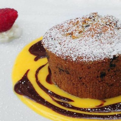 Tortino al cioccolato con salsa e lampone decorativo.