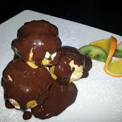 Profiteroles al cioccolato con fette di frutta.