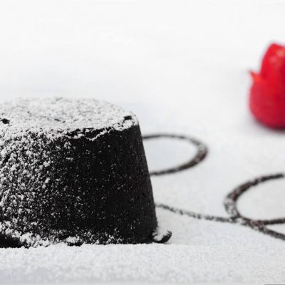 Tortino al cioccolato con zucchero a velo e lampone.