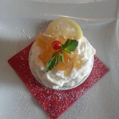 Dessert con panna, limone, menta e ribes su tovagliolo rosso.