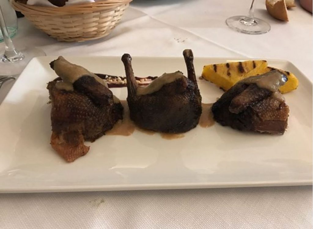 Tre porzioni di carne con polenta su piatto bianco.