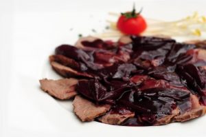 Fettine di carne con salsa scura e pomodoro.
