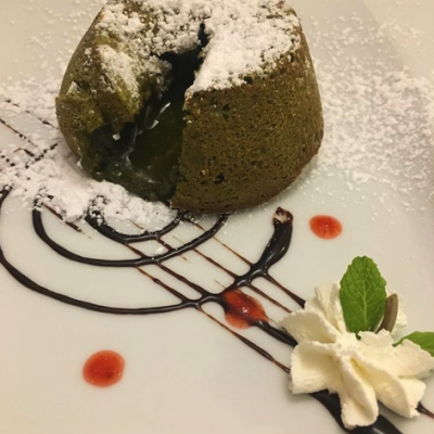 Tortino al cioccolato con crema, panna e decorazioni.