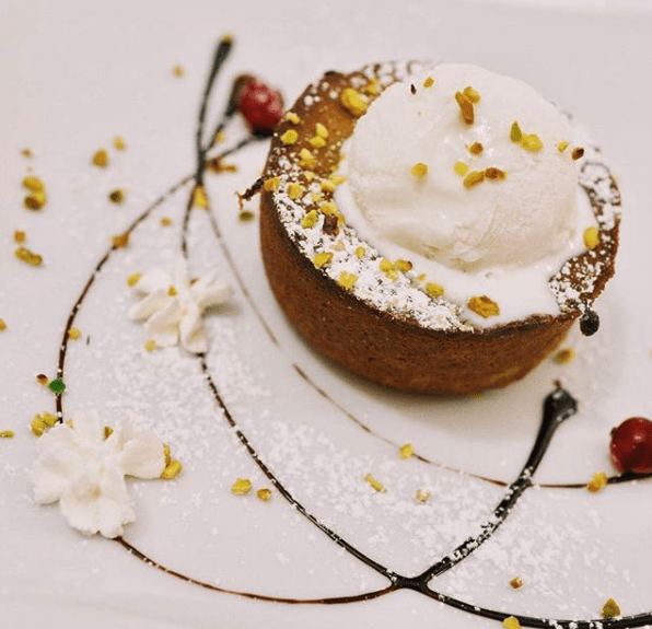 Dolce con gelato, decorato con cioccolato e granella.