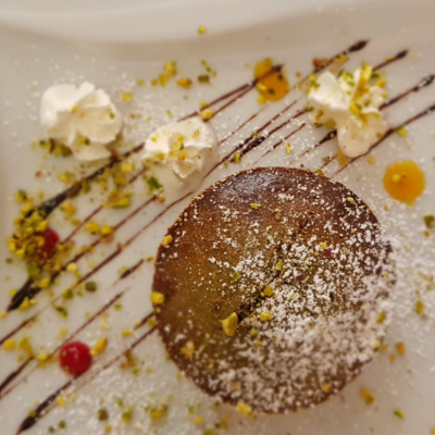 Dolce al cioccolato con panna e granella di pistacchio.