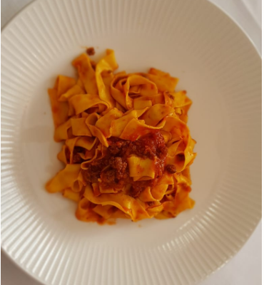 Tagliatelle al ragù su piatto bianco.