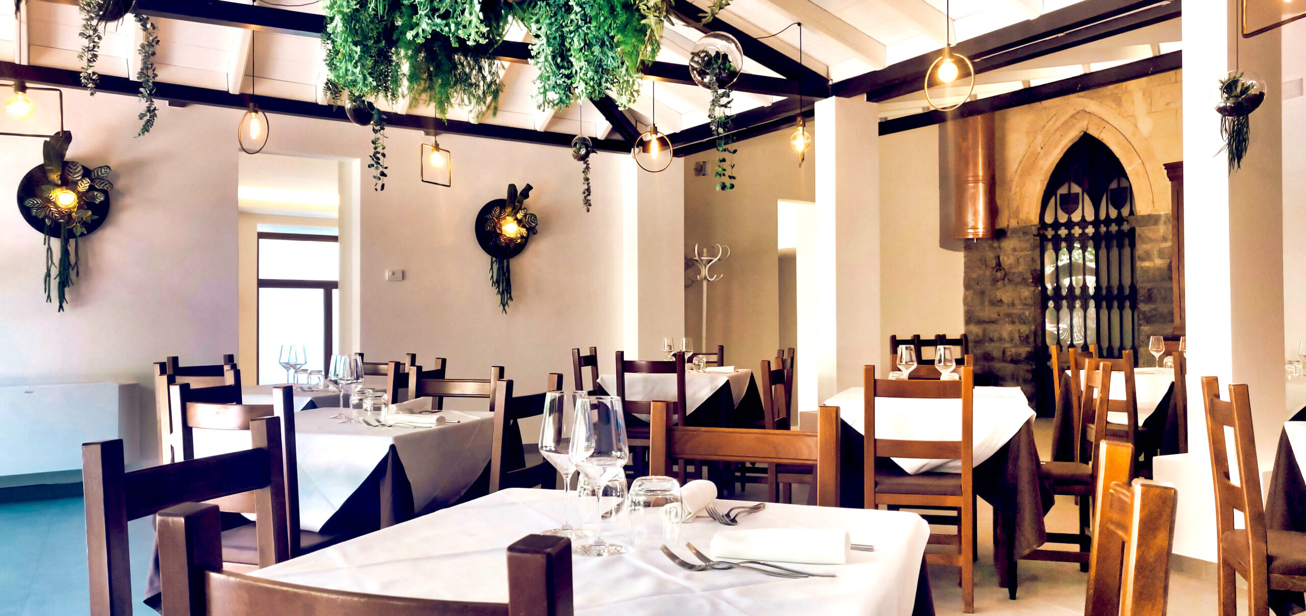 Ristorante elegante con tavoli apparecchiati e decorazioni verdi.
