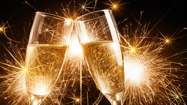 Due calici di champagne con fuochi d'artificio sullo sfondo.